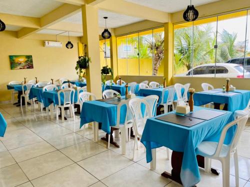 a restaurant with blue tables and white chairs at Hotel Ondas do Mar in Salinópolis