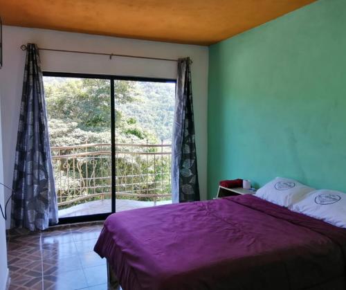 a bedroom with a bed and a large sliding glass door at Hotel El Mirador in Xilitla