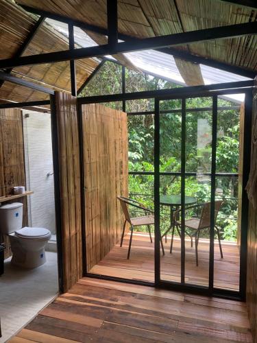 a screened in porch with a table and a toilet at Costeño River Minca in Minca