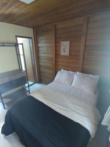 a bedroom with a large bed with a wooden wall at Chalés Schwambach in Domingos Martins