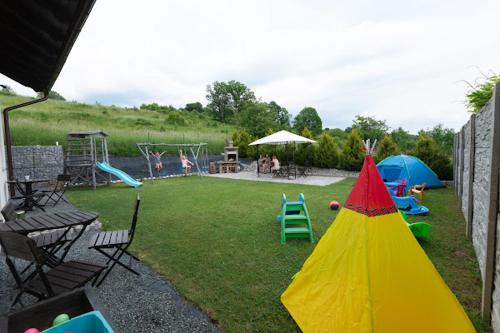 einen Hinterhof mit einem Spielplatz mit Zelt und Stühlen in der Unterkunft Natalii in Kudowa-Zdrój
