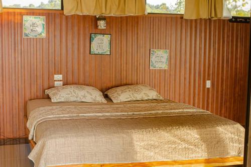 a bedroom with a large bed with two pillows at Corcovado Green Cabin & House in Drake