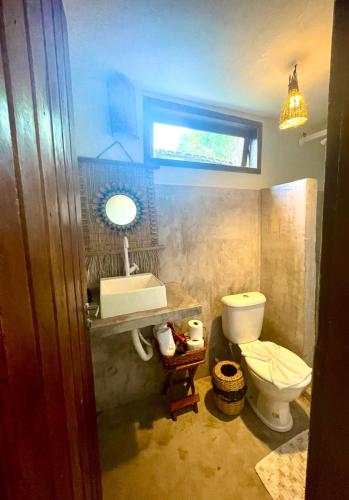 a bathroom with a toilet and a sink and a window at Pousada Jaboticaba Caraíva in Caraíva