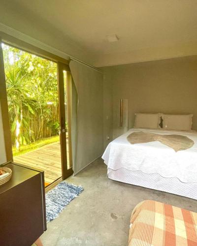 a bedroom with a bed and a sliding glass door at Pousada Jaboticaba Caraíva in Caraíva