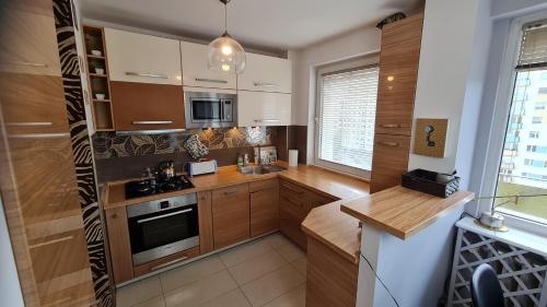 a kitchen with wooden cabinets and a stove top oven at Apartament z widokiem na las in Sopot