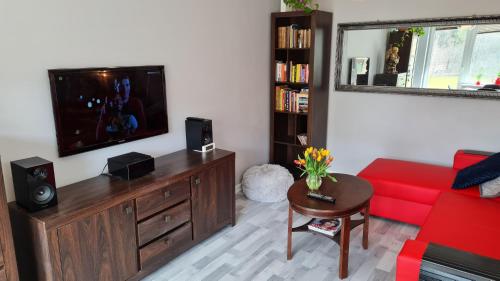 a living room with a red couch and a flat screen tv at Apartament z widokiem na las in Sopot