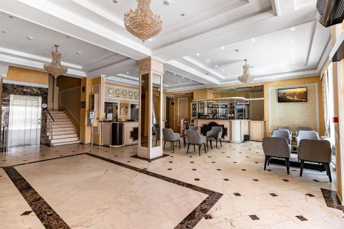 a lobby with chairs and tables and a staircase at Regency Hotel in Chişinău