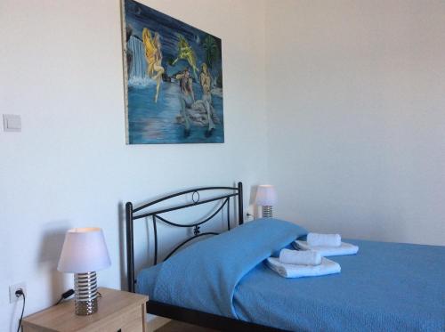a bedroom with a blue bed with a picture on the wall at Soultana’s house in Mourteri