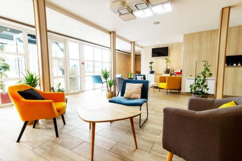 - un hall de bureau avec des chaises et une table dans l'établissement BRIT Hotel Rouen Nord - Barentin, à Barentin