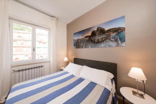 a bedroom with a blue and white striped bed and a window at Poseidon Apartment 011019-LT-0180 in Monterosso al Mare