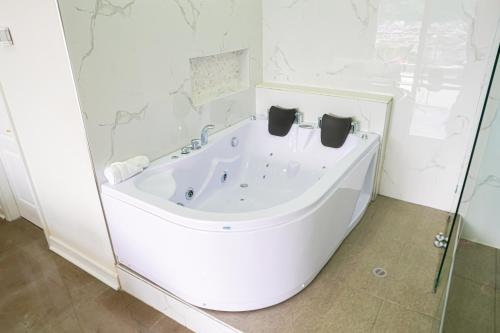 uma banheira na casa de banho com uma parede de vidro em THE VIEW HOTEL em Cumanda