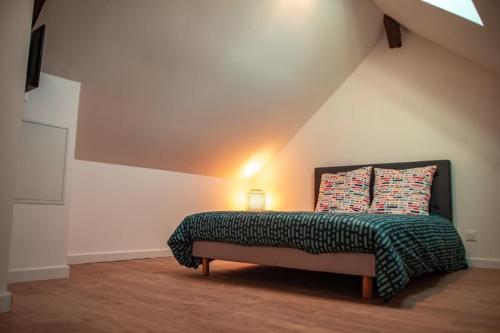 a bedroom with a bed with a green blanket and pillows at Vernon, Le Pacia in Vernon
