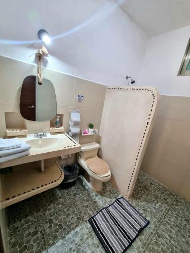 a bathroom with a sink and a toilet and a mirror at Casa aloha-Isla Holbox in Holbox Island
