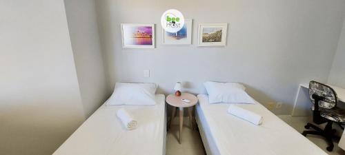 two beds in a room with a table between them at COSTE0100 - Residencial Luz das Acácias in Salvador