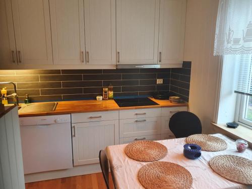 uma cozinha com armários brancos e uma mesa com chapéus em Sjarmerende feriehus i Olden rett ved fjorden em Stryn