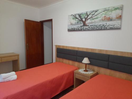 1 dormitorio con 2 camas y un árbol en la pared en Moradia Rodrigues, en Caminha