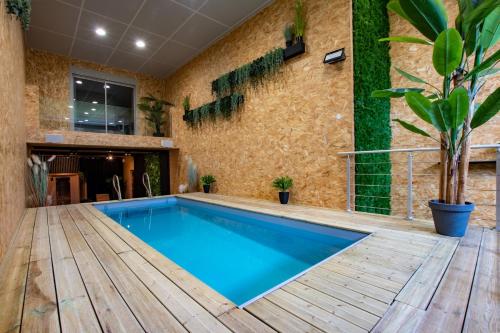 une piscine avec une terrasse en bois et un mur en briques dans l'établissement Loft Haut de gamme en Champagne, à Isles-sur-Suippe