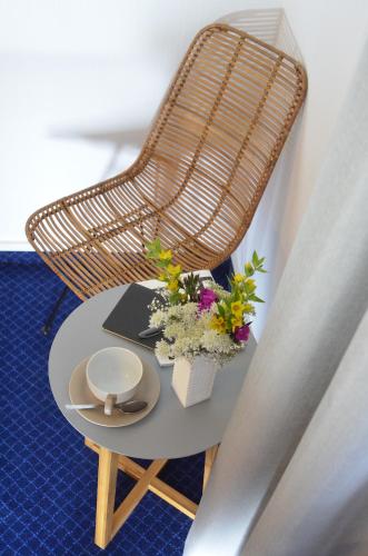 a wicker chair and a table with flowers on it at Alpenrose Bayrischzell Hotel in Bayrischzell