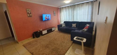 a living room with a blue couch and a window at 3Bedroom Greatwall Gardens Mombasa Rd NBO in Makandara