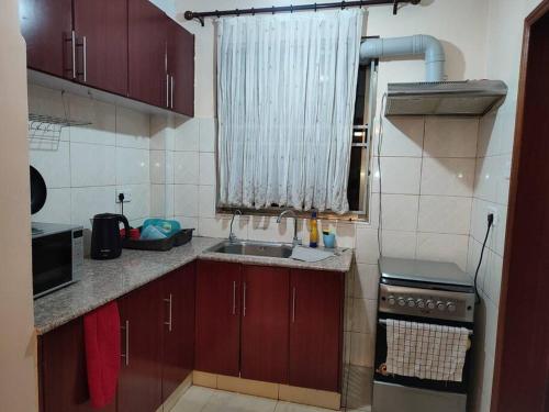 una pequeña cocina con fregadero y ventana en 3Bedroom Greatwall Gardens Mombasa Rd NBO, en MakandaraHousing Estate
