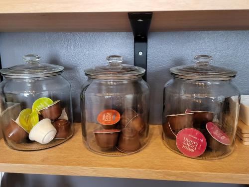 quatre bocaux en verre assis sur une étagère avec des boutons dans l'établissement Appartement centre ville chic et cozy, à Vendôme