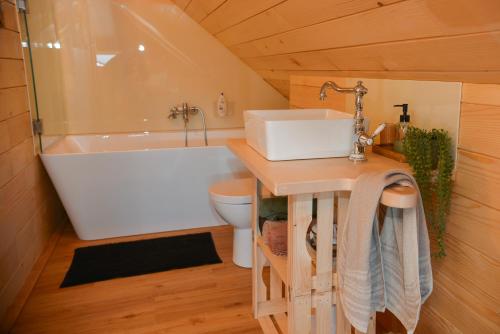 een badkamer met een bad, een wastafel en een toilet bij Glamping Happiness with Sauna and Natural Pool in Ribnica
