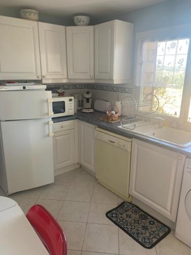une cuisine avec des armoires blanches et des appareils électroménagers blancs dans l'établissement Bas de Villa avec vue dégagée, à Mandelieu-la-Napoule