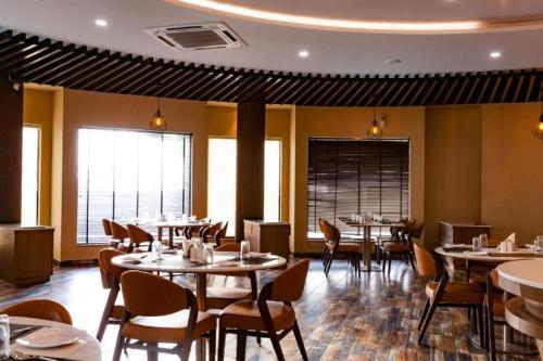 a restaurant with tables and chairs in a room at The Sky Imperial Bapu's Resort in Dwarka