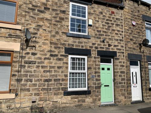 a brick building with two green doors and windows at Contemporary & Chic inner terrace 5 mins from Barnsley town centre in Barnsley