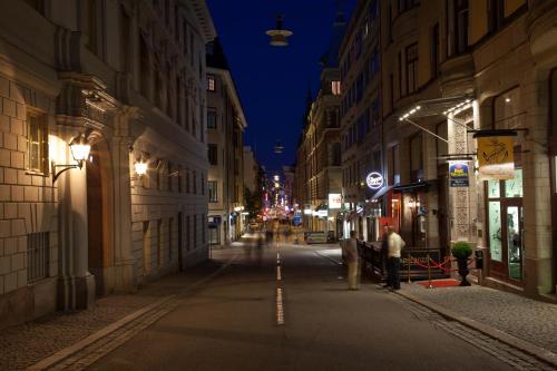a city street at night with people standing on the sidewalk at Best Western Hotel Bentleys in Stockholm