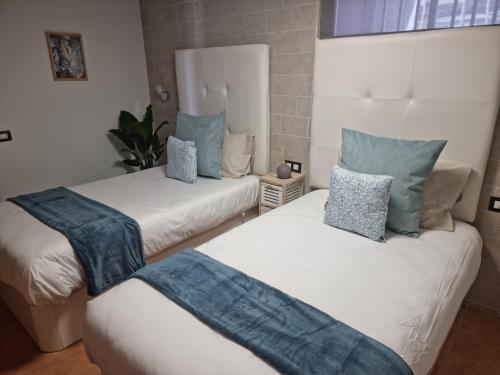 two beds with blue pillows on them in a room at VILLA GAELCA in Arona