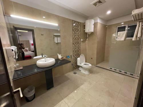 a bathroom with a sink and a toilet and a mirror at Grand Mongolia Hotel in Rawalpindi