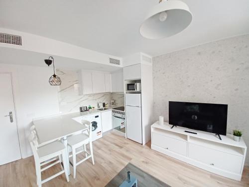 Il comprend une cuisine blanche avec une table à manger et une télévision. dans l'établissement CARTAGENAFLATS, Apartamentos Anfiteatro Romano 4A, à Carthagène