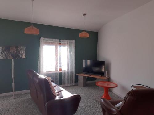 a living room with a couch and a television at Les Verveines in Saint-Martin-dʼArdèche