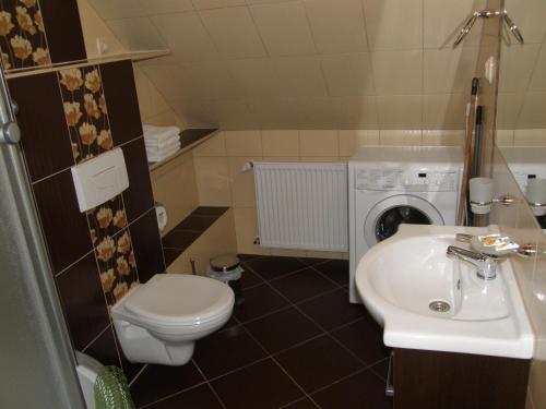 a bathroom with a toilet and a sink and a washing machine at Apartament Fregata in Kołobrzeg