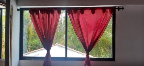 a window with red curtains in a room at Cabañas El Olimpo in Necoclí