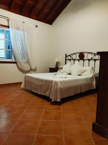 a bedroom with a bed with white sheets and a window at Casa sol y montaña in Cubaba