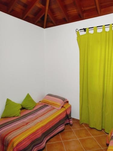 a bedroom with a bed and a green curtain at Casa sol y montaña in Cubaba