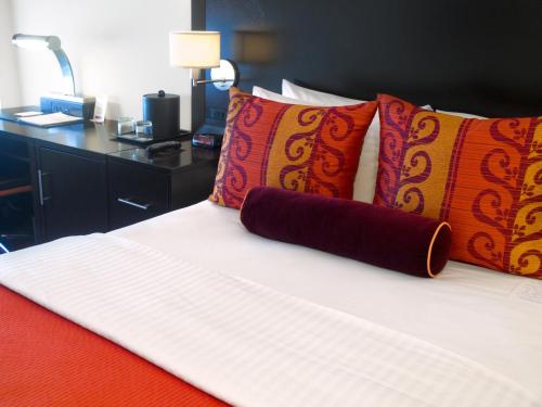 a bed with red and orange pillows and a desk at Washington Plaza Hotel in Washington