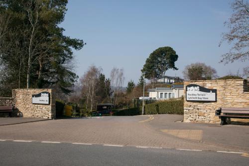 a parking lot with two gates and a bench at 51 Lytchett Bay View, 3 bed, Rockley Park Poole in Poole