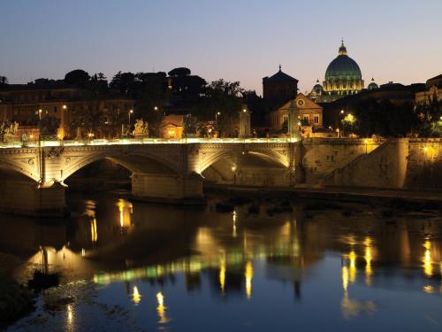 a bridge over a river with a city in the background at Rocco Forte Hotel De Russie in Rome