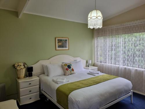 a bedroom with a white bed and a window at Beech Forest Cottage (Cozy Otways Accommodation) in Beech Forest