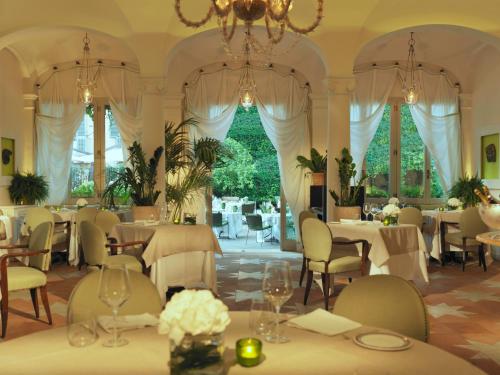 a restaurant with tables and chairs and a chandelier at Rocco Forte Hotel De Russie in Rome