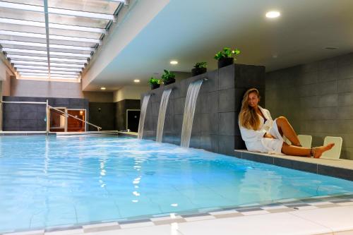 a woman sitting in a chair next to a swimming pool at Kn Aparthotel Columbus in Playa de las Americas