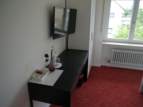 a room with a black desk with a tv on the wall at Mille Stelle Hotel in Eggenstein-Leopoldshafen