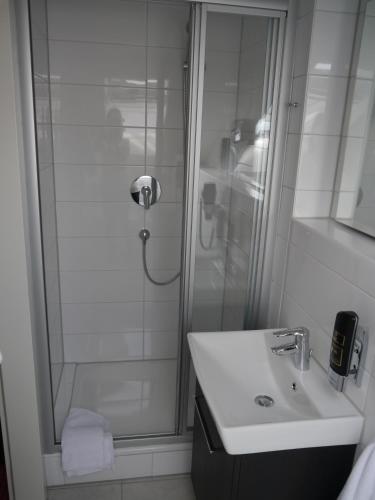 a white bathroom with a shower and a sink at Mille Stelle Hotel in Eggenstein-Leopoldshafen