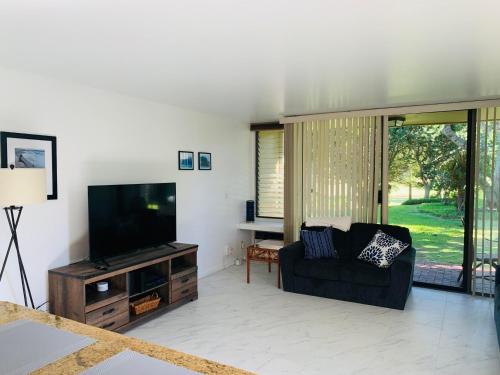 a living room with a couch and a flat screen tv at Cozy & Peaceful North Shore Oasis at Turtle Bay in Kahuku