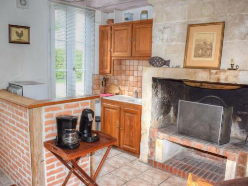 a kitchen with a fireplace with a sink and a stove at Gîte Cheillé, 2 pièces, 3 personnes - FR-1-381-417 in Cheillé