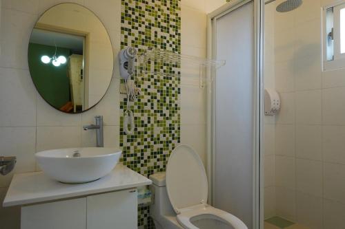 een badkamer met een wastafel, een toilet en een spiegel bij Provence Homestay in Magong