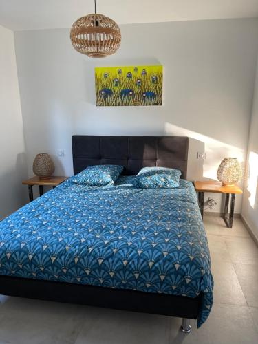 - une chambre avec un lit avec une couette bleue et 2 tables dans l'établissement Villa l'art de fer, à Saint-Paul-de-Vence